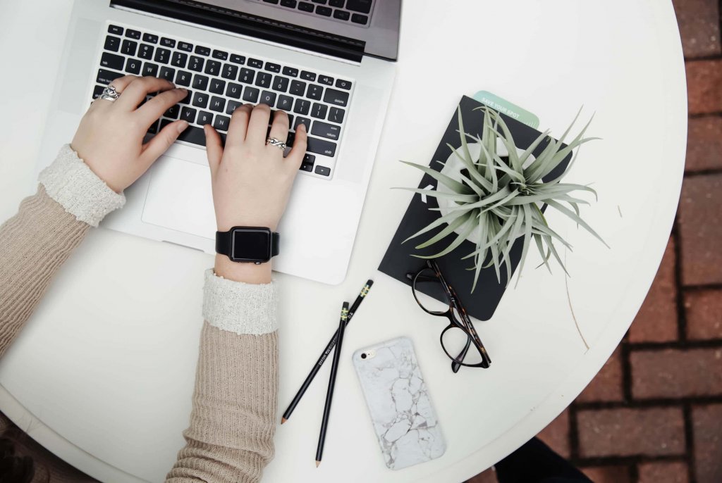 social media manager - hands with apple watch glasses and laptop on a table