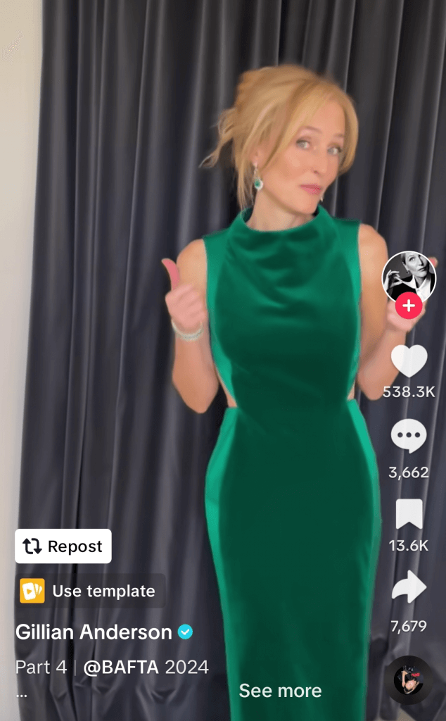 TikTok post of Gillian Anderson in a green dress posing with a thumbs-up at a BAFTA event.