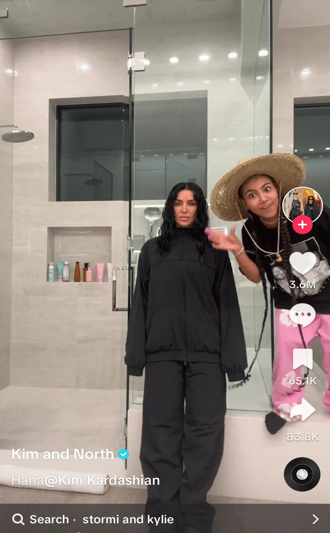 Two women in a modern bathroom, one in casual black attire and the other in a playful outfit with a sombrero, featured in a social media video.