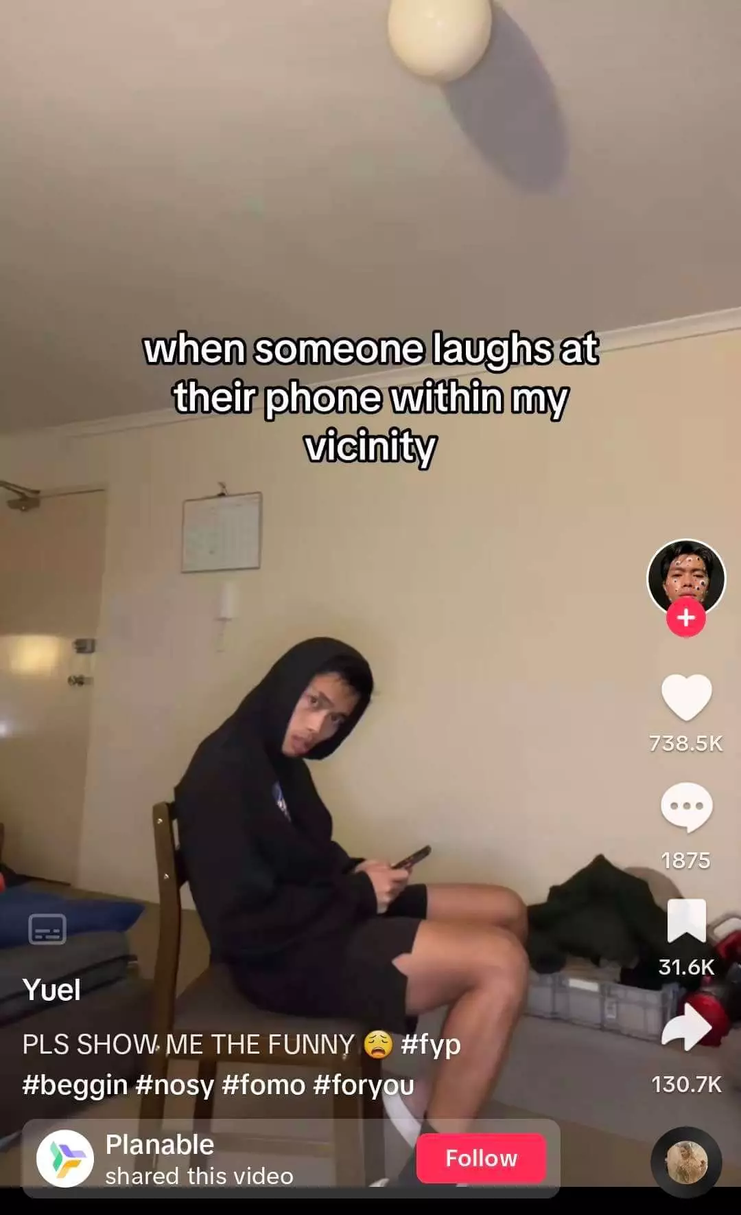 Young person in a hoodie sitting on a chair, giving a curious look while holding a smartphone, humorously depicted in a social media post about overhearing laughter.