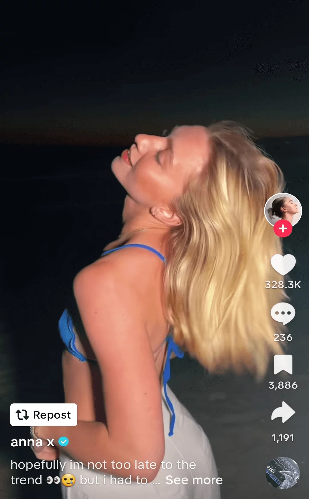 TikTok of a young woman in a blue swimsuit tilting her head back with eyes closed, enjoying a breezy evening at the beach, on a social media platform.