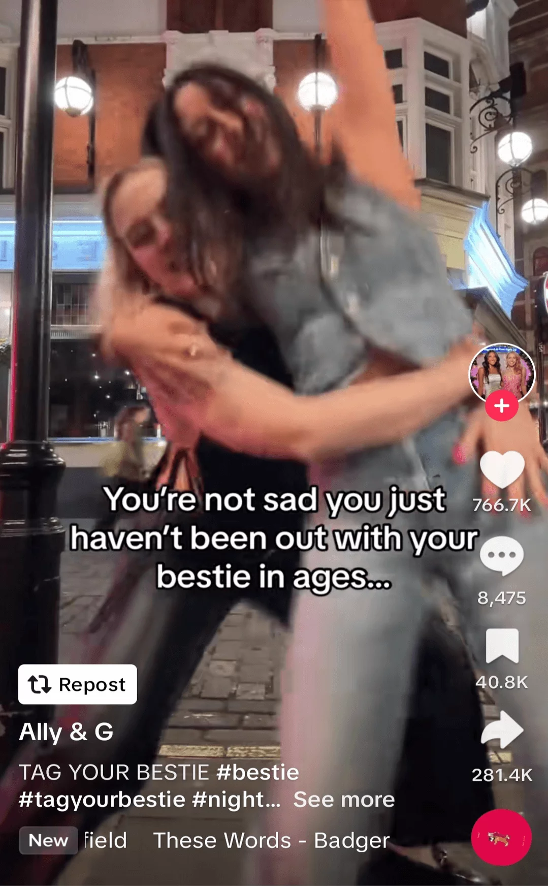 Two friends joyfully hugging and spinning on a city street at night, captured in a lively, blurred motion social media post.