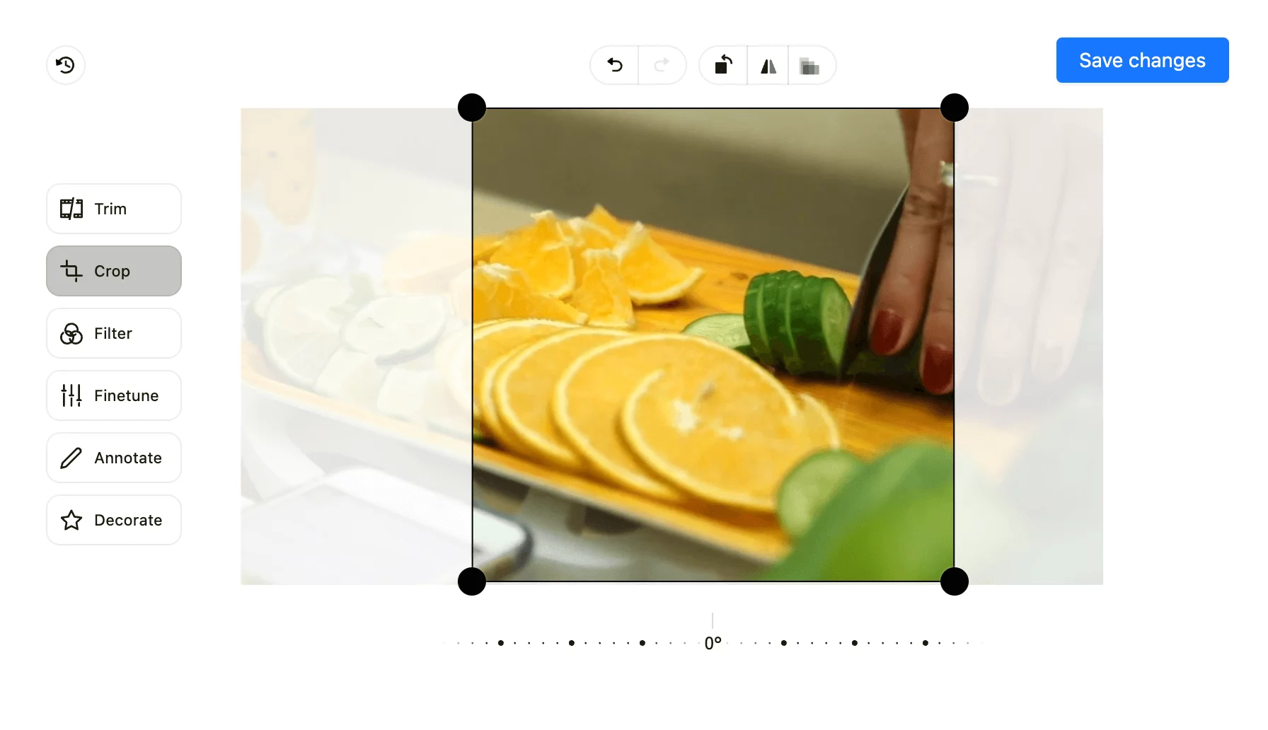 Image and video editing interface in Planable with a cropping tool being used on a photo of sliced oranges and cucumbers on a wooden board.