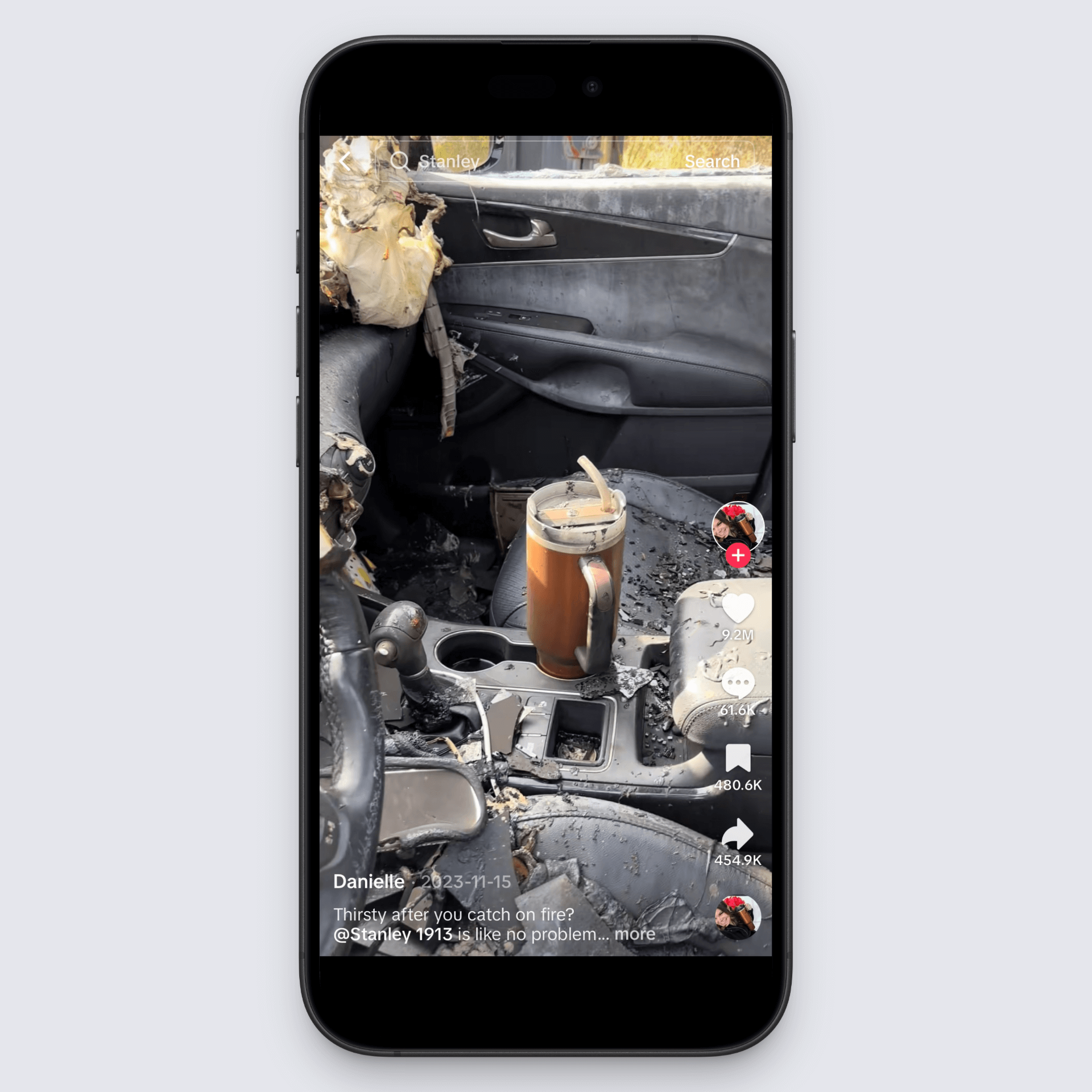 Burned car interior with intact Stanley cup in cupholder, showcasing product durability after fire.