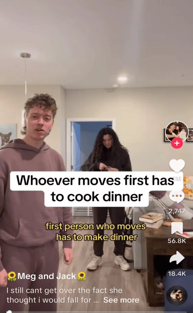 TikTok post of a couple standing in their living room, captioned 'whoever moves first has to cook dinner'.
