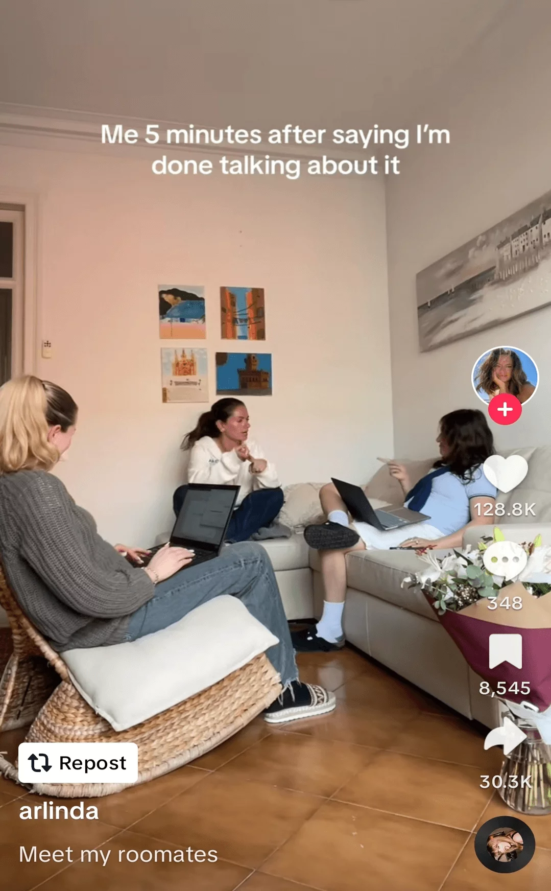 Three roommates engaged in a lively conversation in a cozy living room decorated with various paintings.