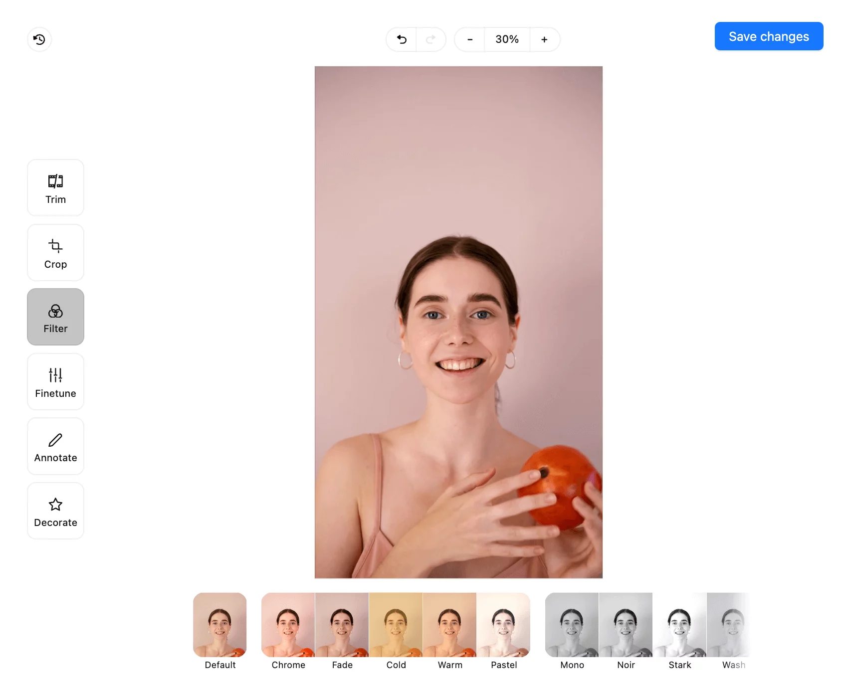 Video editing interface showing a smiling woman holding an orange, with options to trim, crop, apply filters, finetune, annotate, and decorate the image.